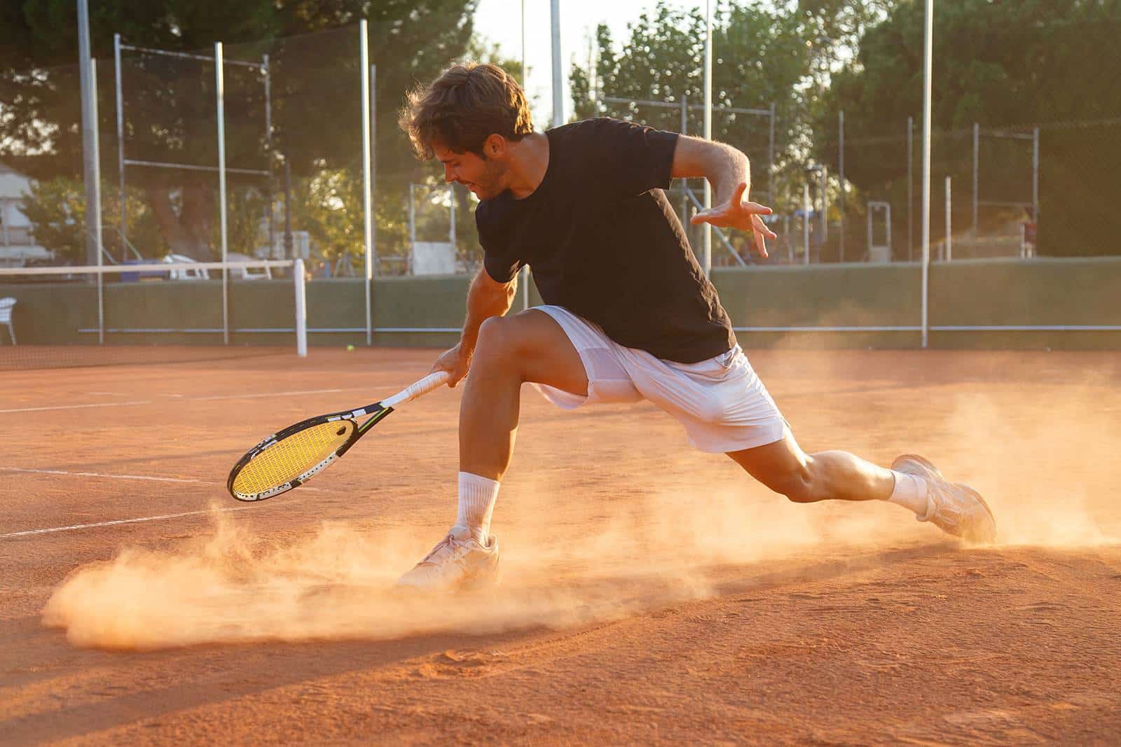 Ein Mann spielt Tennis auf einem Sandplatz.